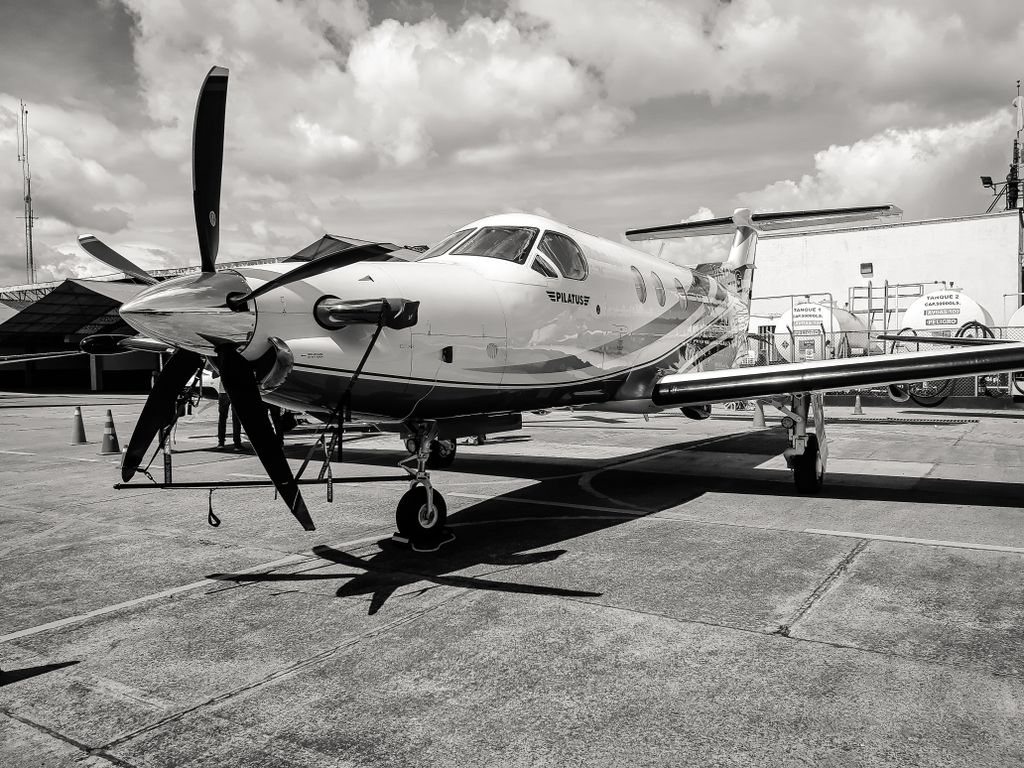 Black and white image of a modern aircraft at Bogotá airport under a cloudy sky.